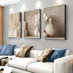 Three framed artworks on a wall above a white sofa with decorative pillows.