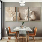 Dining room with a table set for four, three floral wall art pieces on the wall, and a vase on the table.