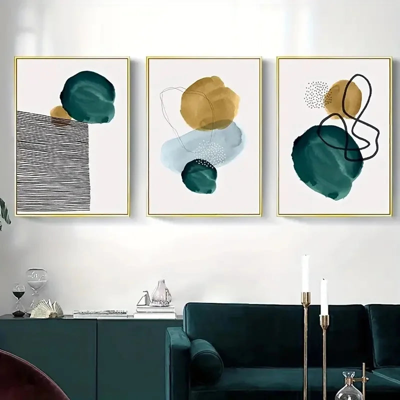 Abstract art prints on a wall above a dark green sofa in a living room.