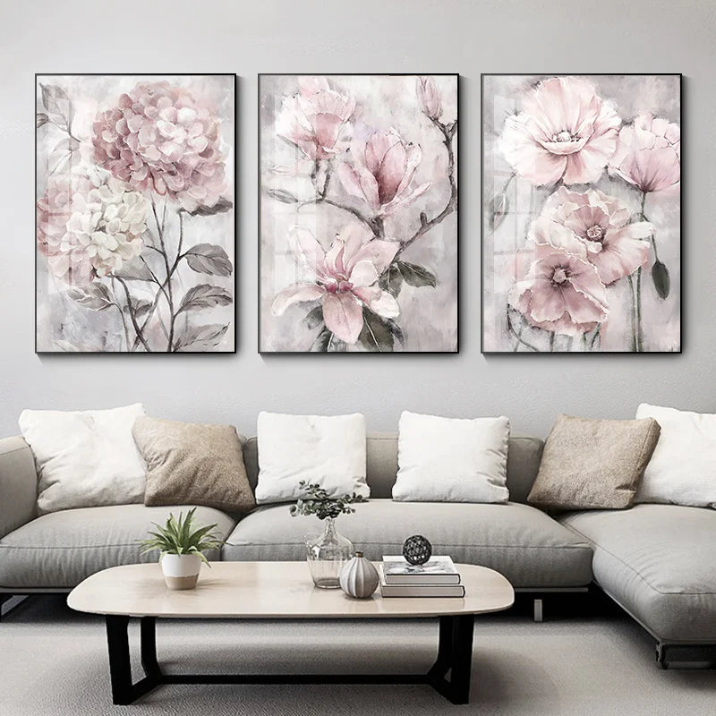 Three floral paintings above a gray sofa in a living room setting.