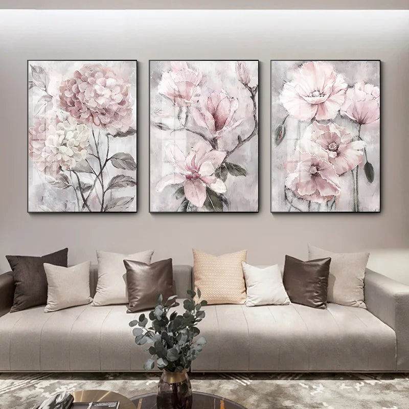 Three floral paintings above a sofa in a living room setting.