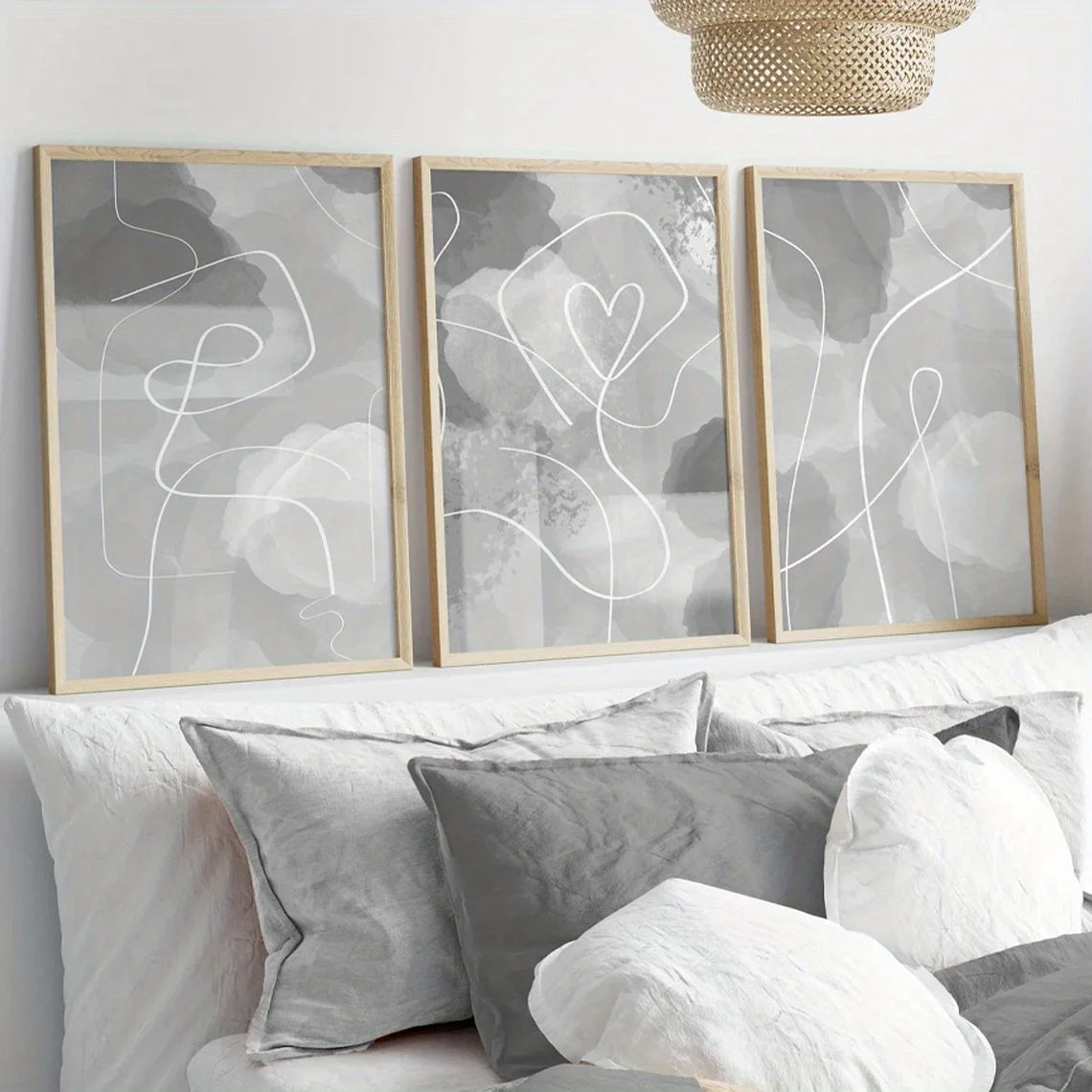 Three abstract line art prints on a wall above a sofa with cushions.