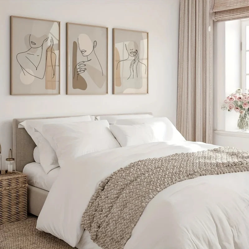 Neatly made bed with white bedding and a beige throw blanket, framed abstract art on the wall.