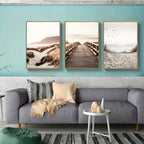 Living room with a gray sofa, decorative pillows, and three framed beach scenes on the wall.