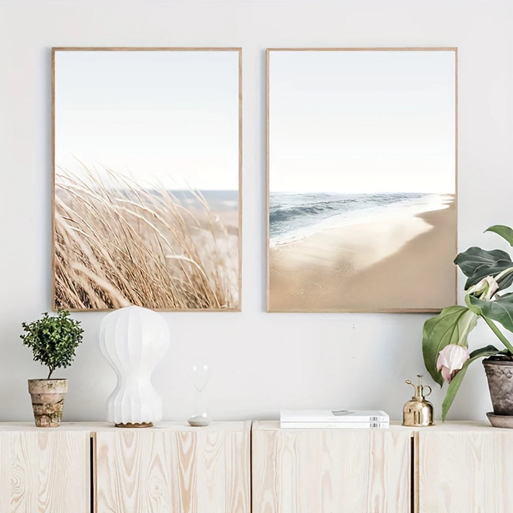 Two framed beachscape prints on a wall above a wooden cabinet with decorative items.