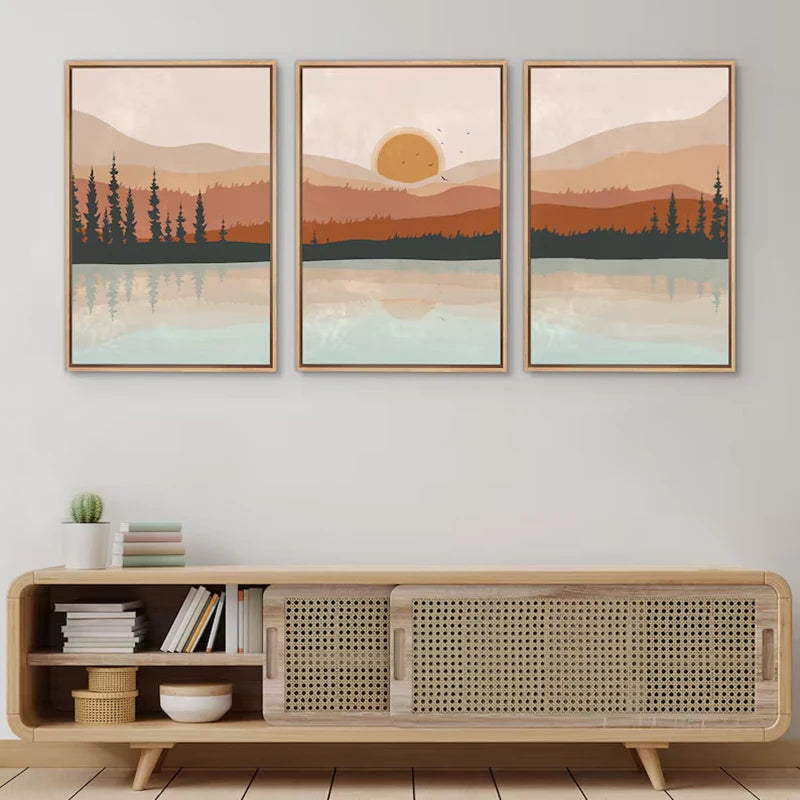 Three framed landscape paintings above a wooden cabinet with wicker design.