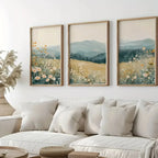 Three framed landscape paintings above a white sofa in a living room.