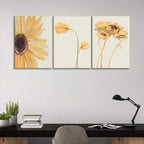 Three floral paintings on a wall above a desk with a lamp and books.