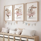Three framed illustrations of a rabbit in a tutu on a wall above a wooden bench with cushions.