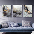 Three abstract art pieces on a wall above a sofa with decorative pillows.