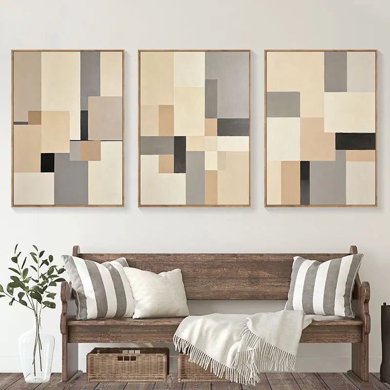 Three abstract wall art pieces above a wooden bench with decorative pillows and a plant.