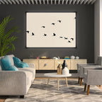 Modern living room with gray sofa, armchair, and coffee table, featuring a wall art of black birds.