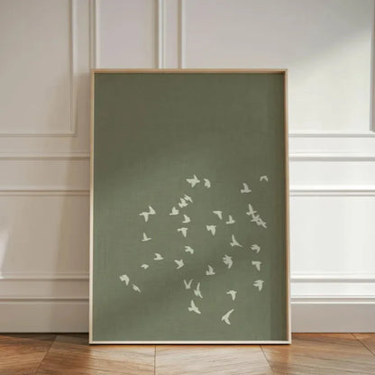 Framed artwork with white bird silhouettes on a green background against a neutral wall.