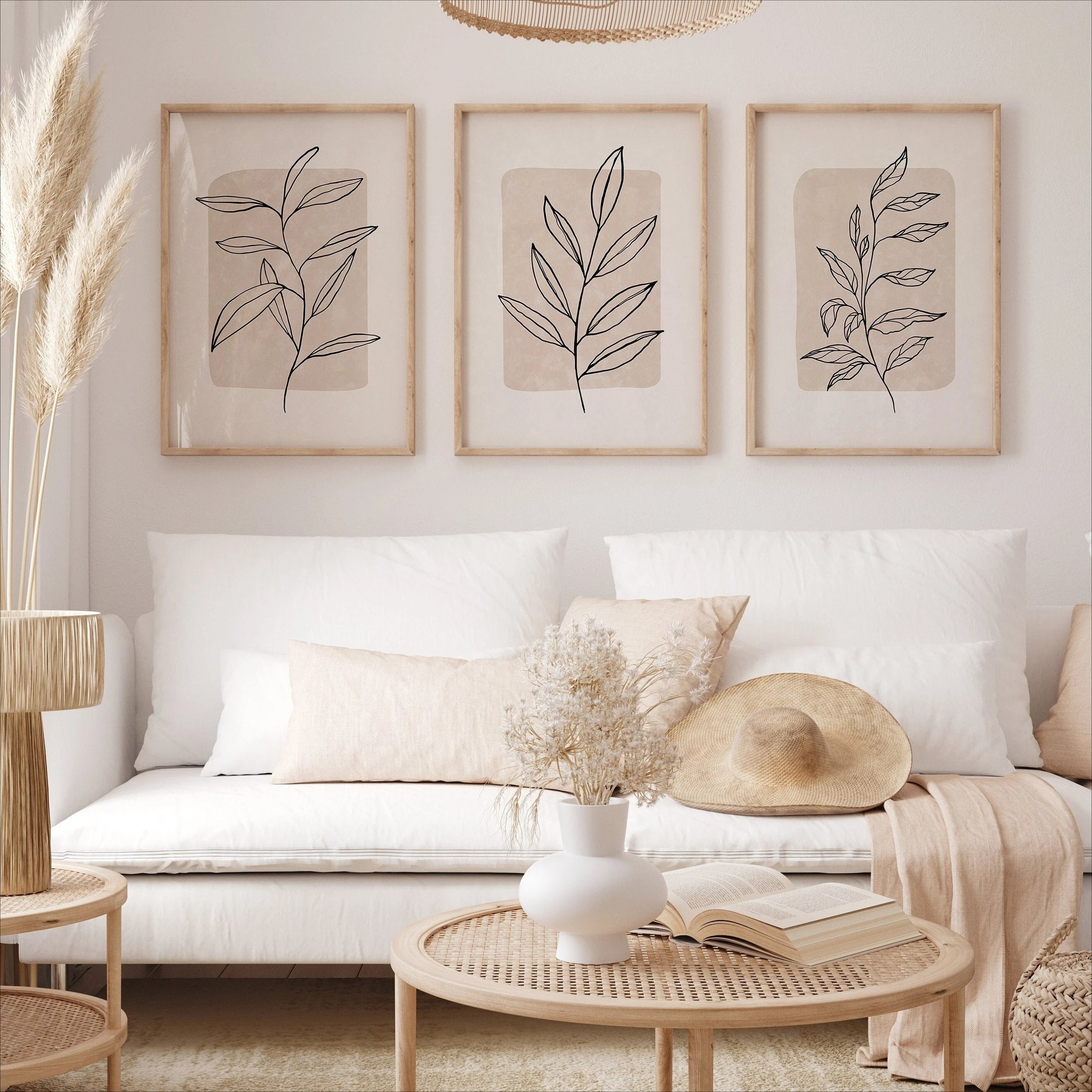 Living room with white sofa, decorative pillows, and wall art featuring leaf designs.