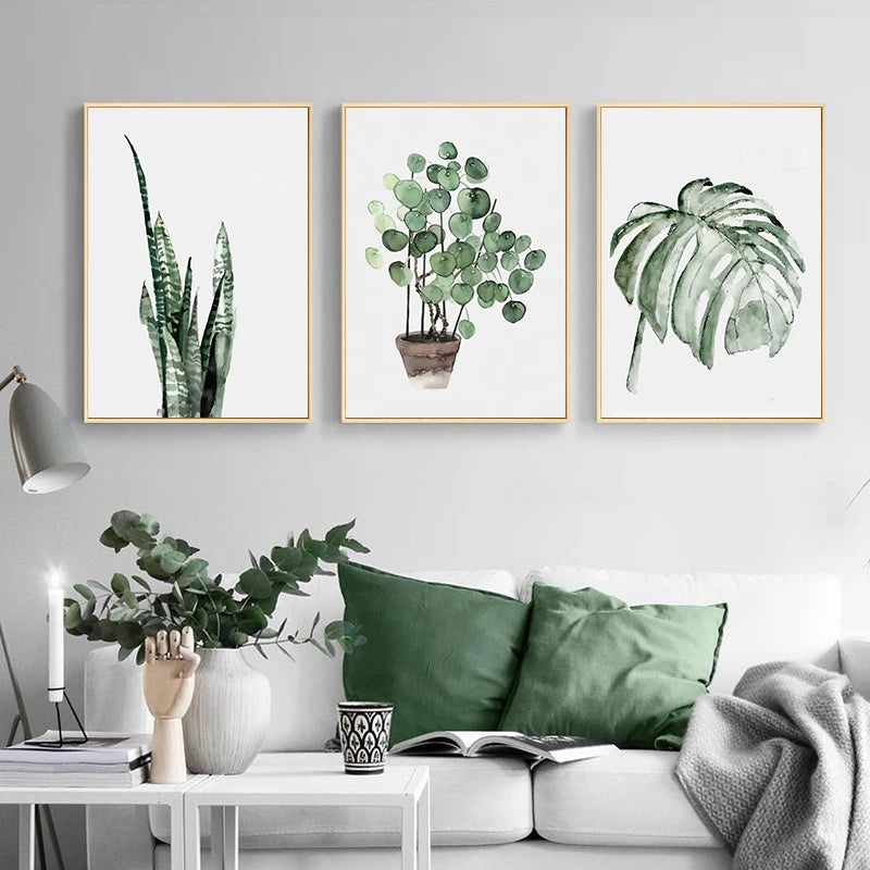 Three framed plant prints on a wall above a sofa with green cushions.
