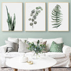 Living room with a white sofa, decorative pillows, and framed botanical prints on the wall.