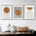 Three abstract art prints with geometric shapes on a wall above a sofa.