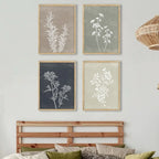 Four framed botanical prints on a wall above a wooden headboard.
