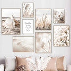 Wall with framed artwork in neutral tones, including beach scenes and floral prints, above a sofa with matching pillows.