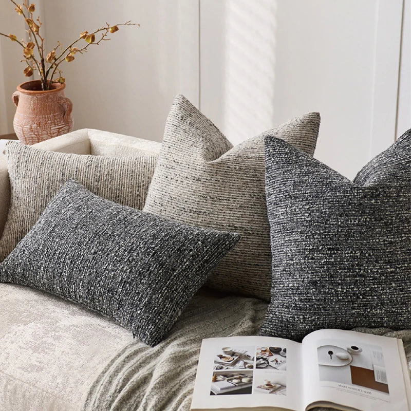Textured throw pillows on a sofa with an open magazine underneath.