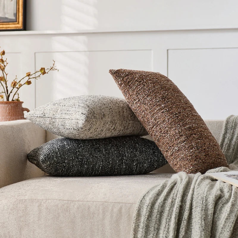 Three textured pillows on a beige sofa with a neutral background