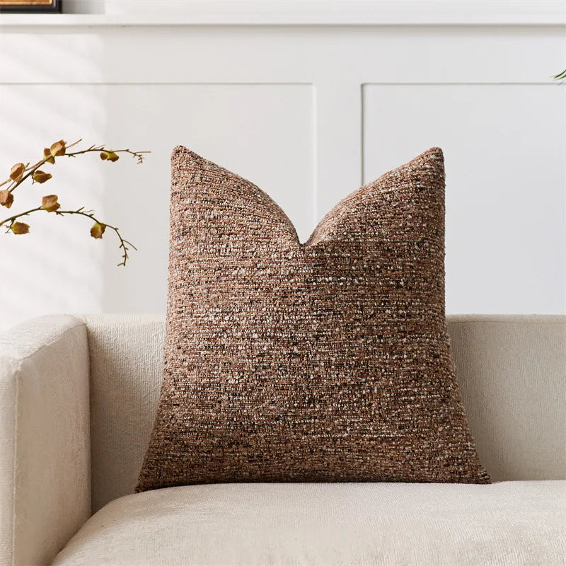 Textured brown pillow on a beige sofa with a white wall in the background
