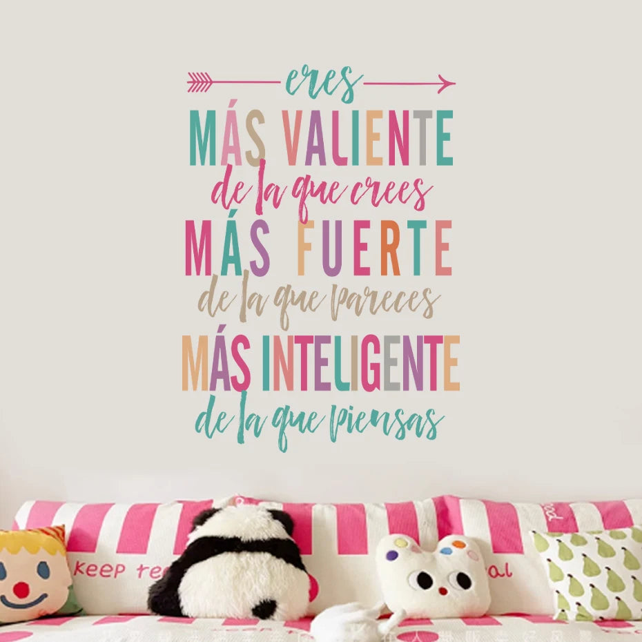 Decorative wall with motivational Spanish text above a pink striped couch with plush toys.