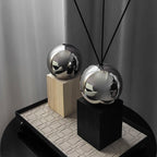 Two metallic spherical objects on wooden and black stands against a neutral background