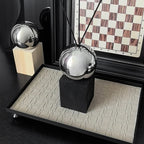 Decorative metallic sphere on a black stand with a checkered board in the background