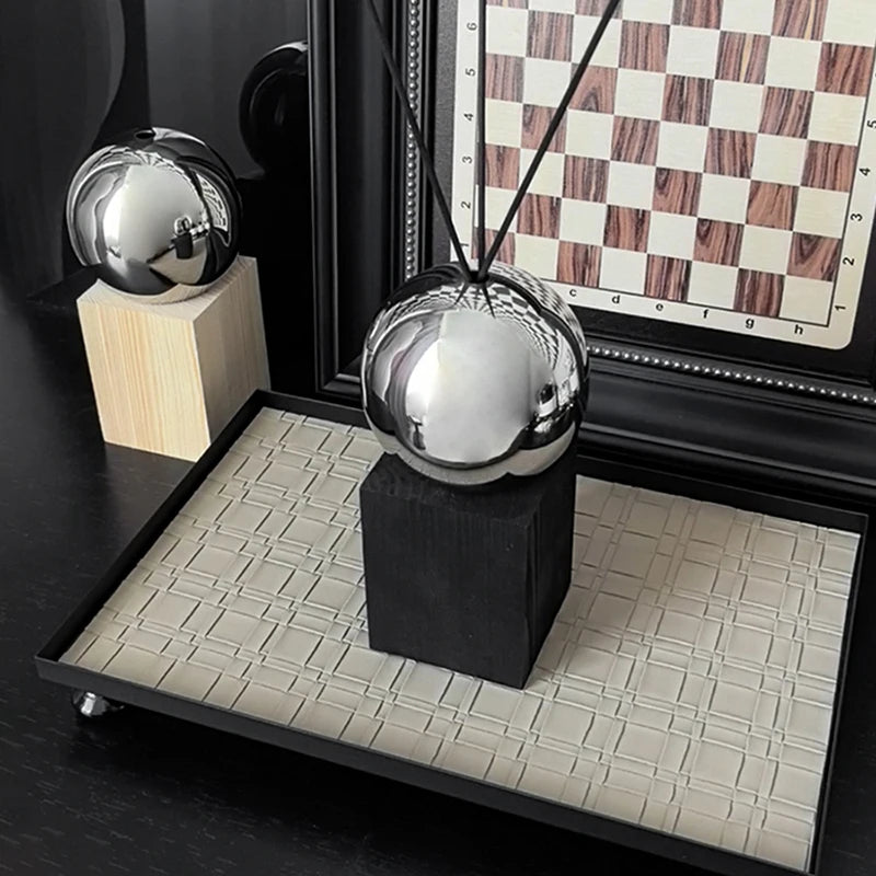 Decorative metallic sphere on a black stand with a checkered board in the background