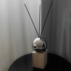 Silver spherical diffuser with black sticks on a white background