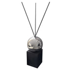 Decorative diffuser with metallic sphere and black sticks on a white background