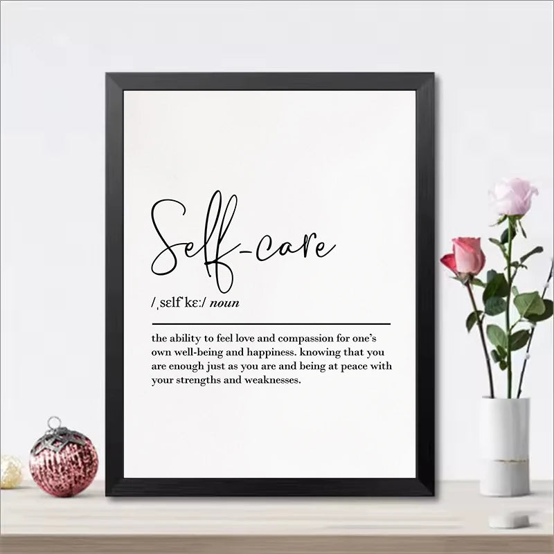 Framed print with 'Self-care' definition on a white wall with decorative items.
