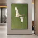 Framed artwork of two swans on a green background in a modern interior setting.