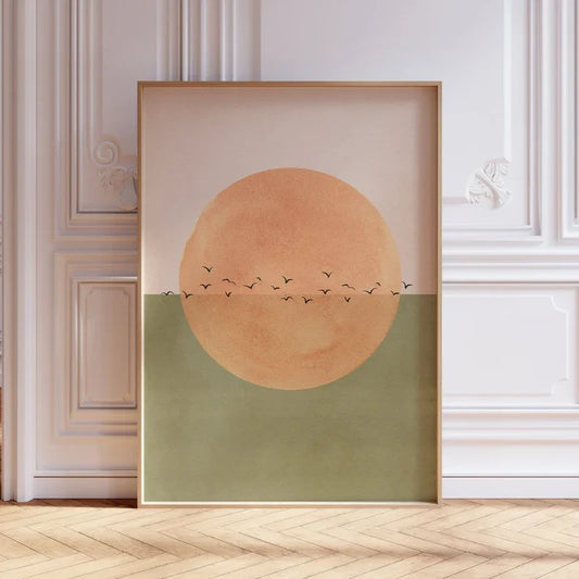 Framed abstract art with a large orange circle and smaller black circles on a beige background, displayed in a room.