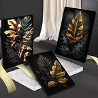 Three decorative panels with gold and black leaf designs on a dark surface.