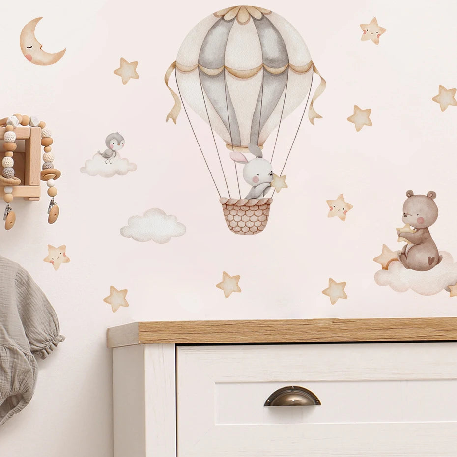 Children's room with wall decals of a hot air balloon and teddy bear, wooden dresser, and mobile.