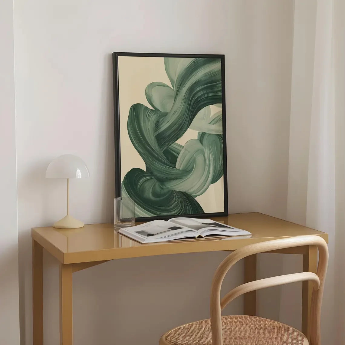 Framed abstract green artwork on a wooden table with a chair in a minimalistic room.