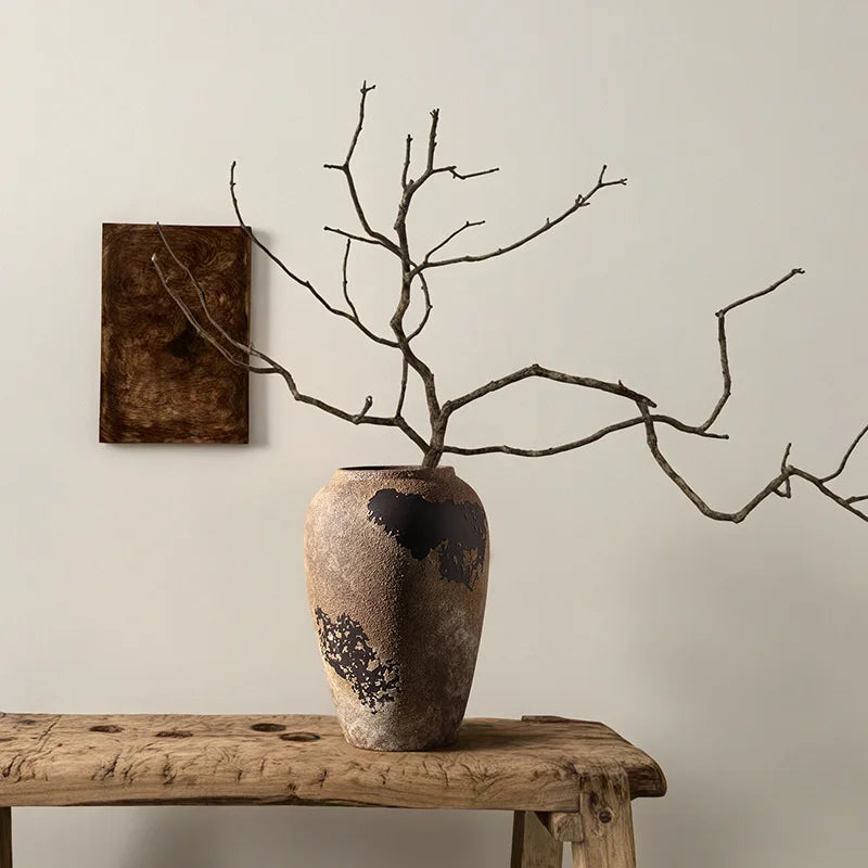 Vase with branches on a wooden table against a neutral wall