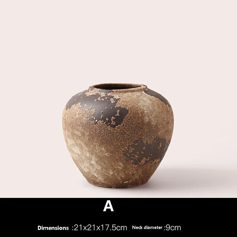Brown ceramic vase with black speckles on a light beige background