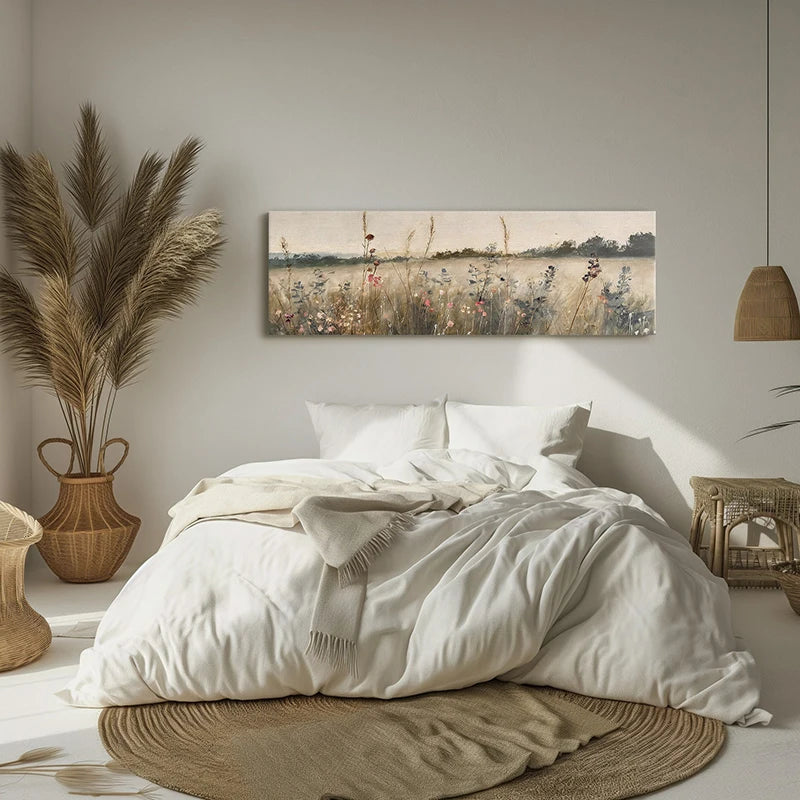 Neatly made bed in a bedroom with a painting of a field on the wall.