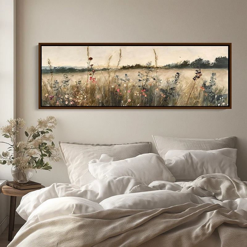 Framed artwork of a field with flowers above a bed in a bedroom.