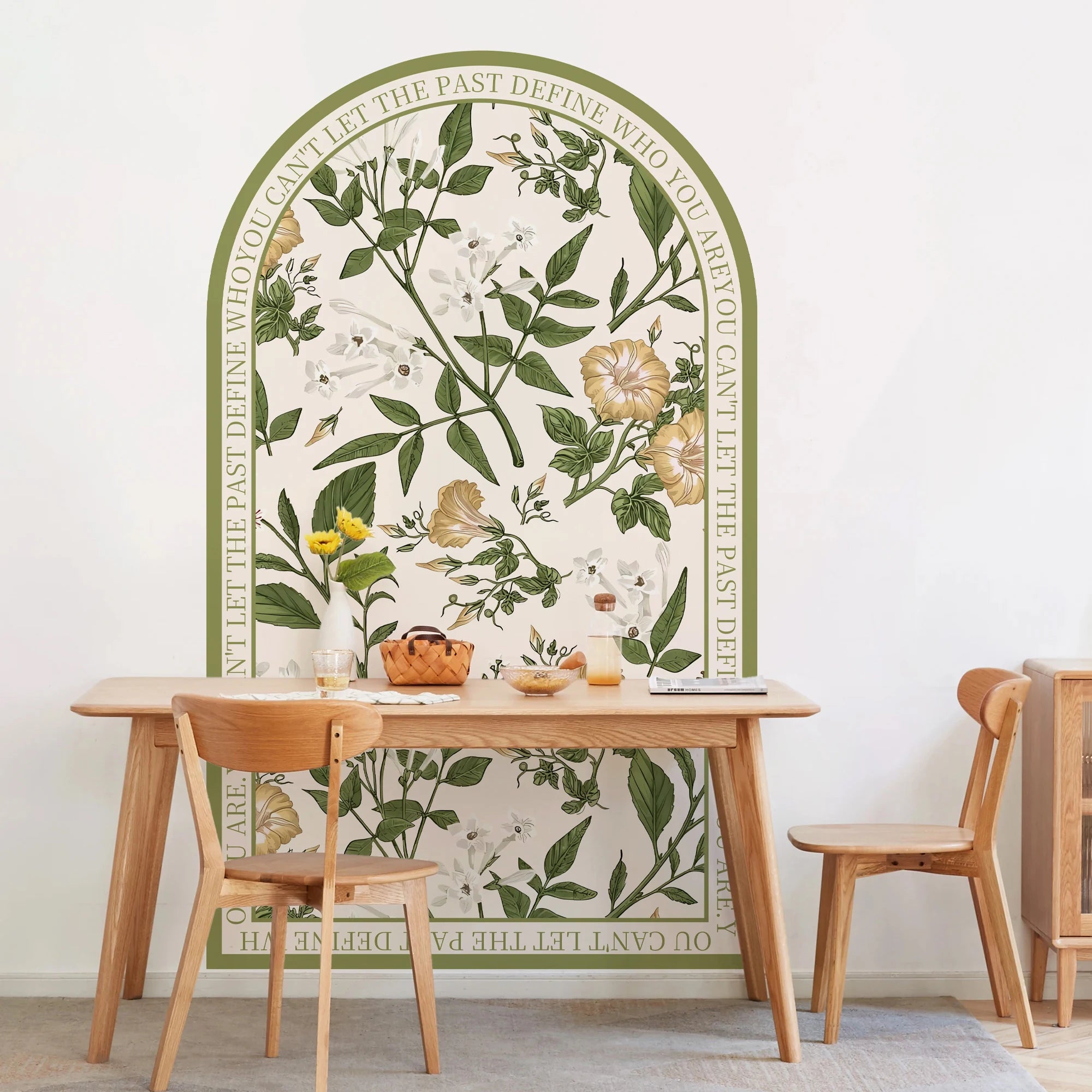 Dining area with a table and chairs in front of a decorative wall mural with floral and botanical design.