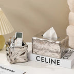 Decorative tissue box with a marble texture on a surface with a 'Celine' book.