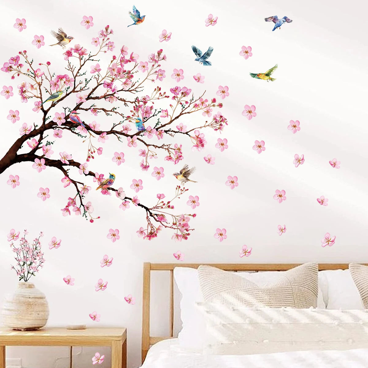 Wall decal of cherry blossom tree with pink flowers and birds in a bedroom setting.