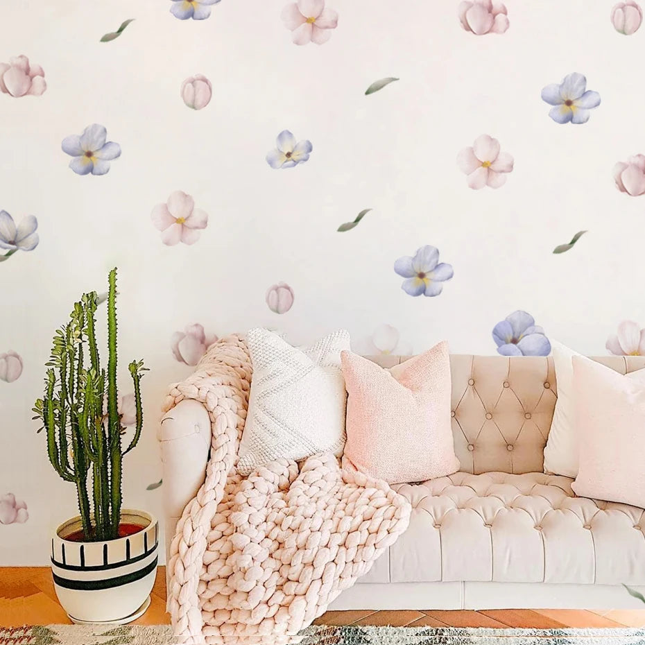 Light pink sofa with decorative pillows and a cactus plant against a floral wallpapered wall.