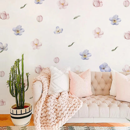 Light pink sofa with decorative pillows and a cactus plant against a floral wallpapered wall.