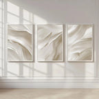 Three abstract wall art pieces in neutral tones on a light wall.