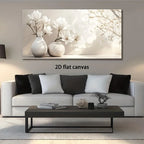 A large rectangular canvas wall art print showing white magnolia flowers in two white vases, displayed above a modern white sofa in a styled living room. The text '2D flat canvas' appears below the artwork.
