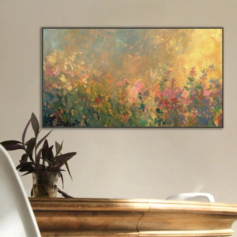 A horizontal canvas print of an impressionistic floral painting, featuring vibrant yellow, pink, green, and blue brushstrokes, displayed on a beige wall above a wooden console table with a potted plant.